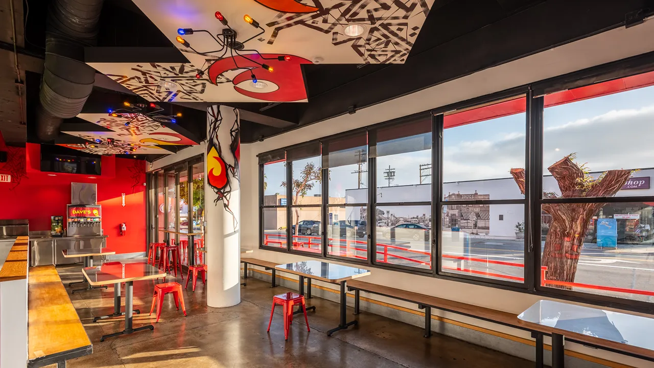 Bright and airy dining space with large windows and red seating at Dave's Hot Chicken on Garnet Ave in Pacific Beach, San Diego, CA.