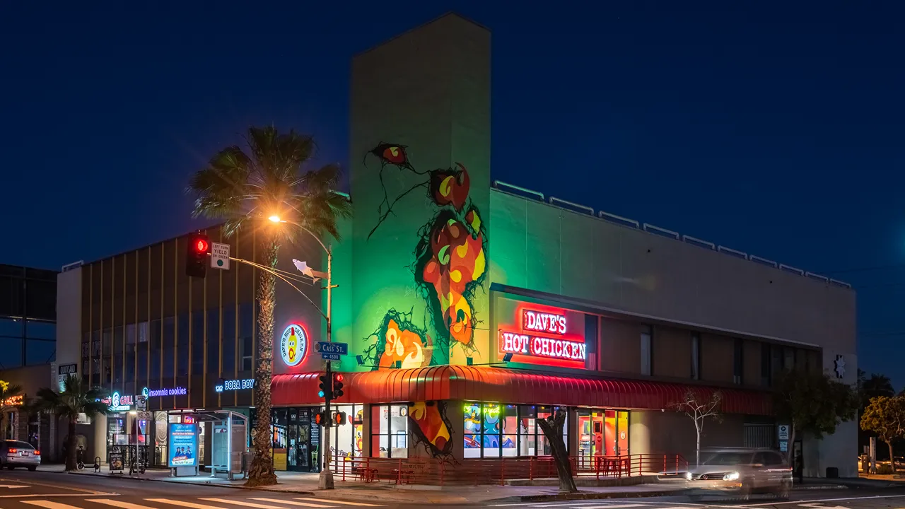 Exterior view of Dave's Hot Chicken with vibrant wall mural at night on Garnet Ave in Pacific Beach, San Diego, CA.