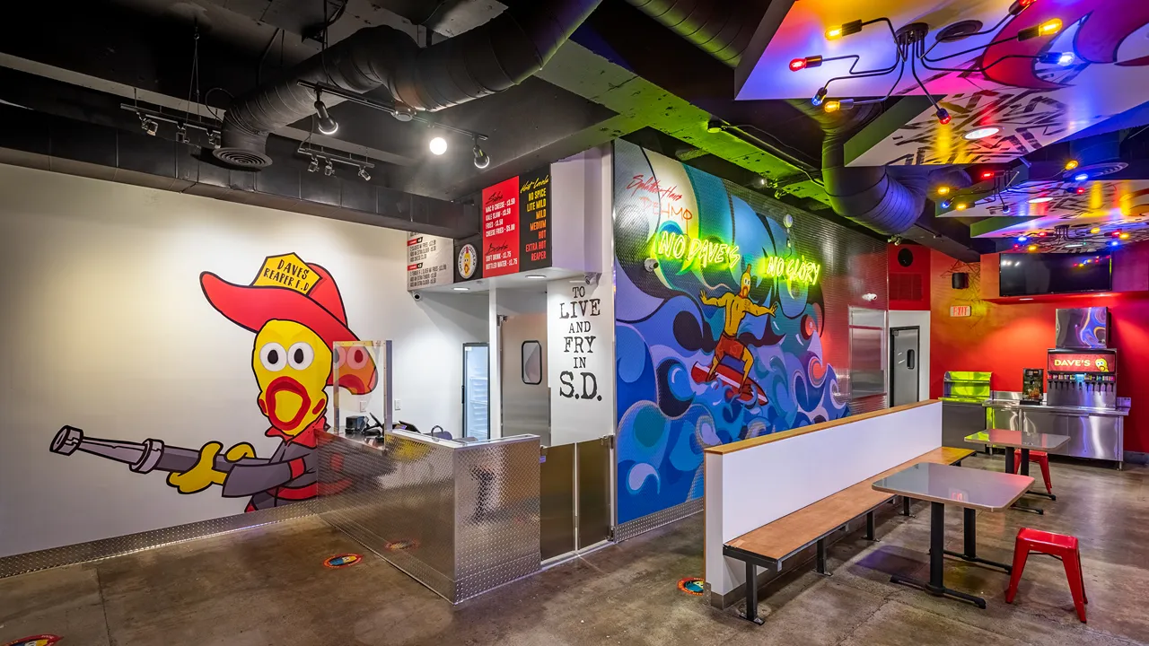 Vibrant interior featuring Dave's Reaper character wall art and colorful neon signage at Dave's Hot Chicken on Garnet Ave in Pacific Beach, San Diego, CA.