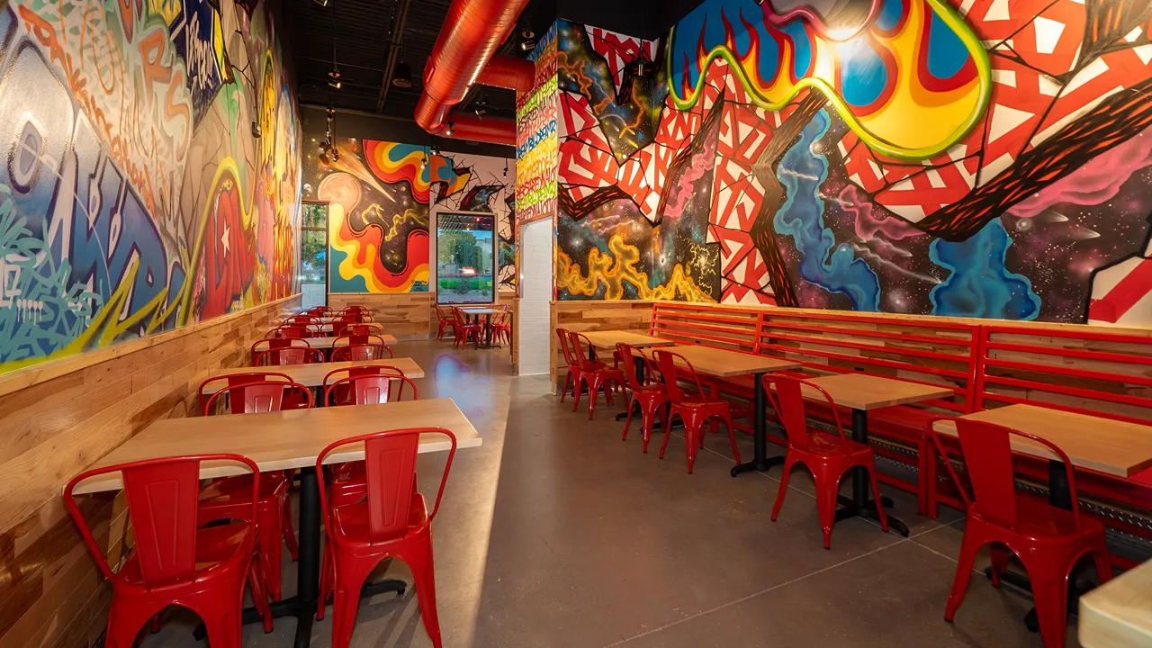 Indoor seating area with bold graffiti-style murals and red furniture at Dave's Hot Chicken, La Picosa on SE Military Drive and South New Braunfels Avenue, San Antonio, TX.