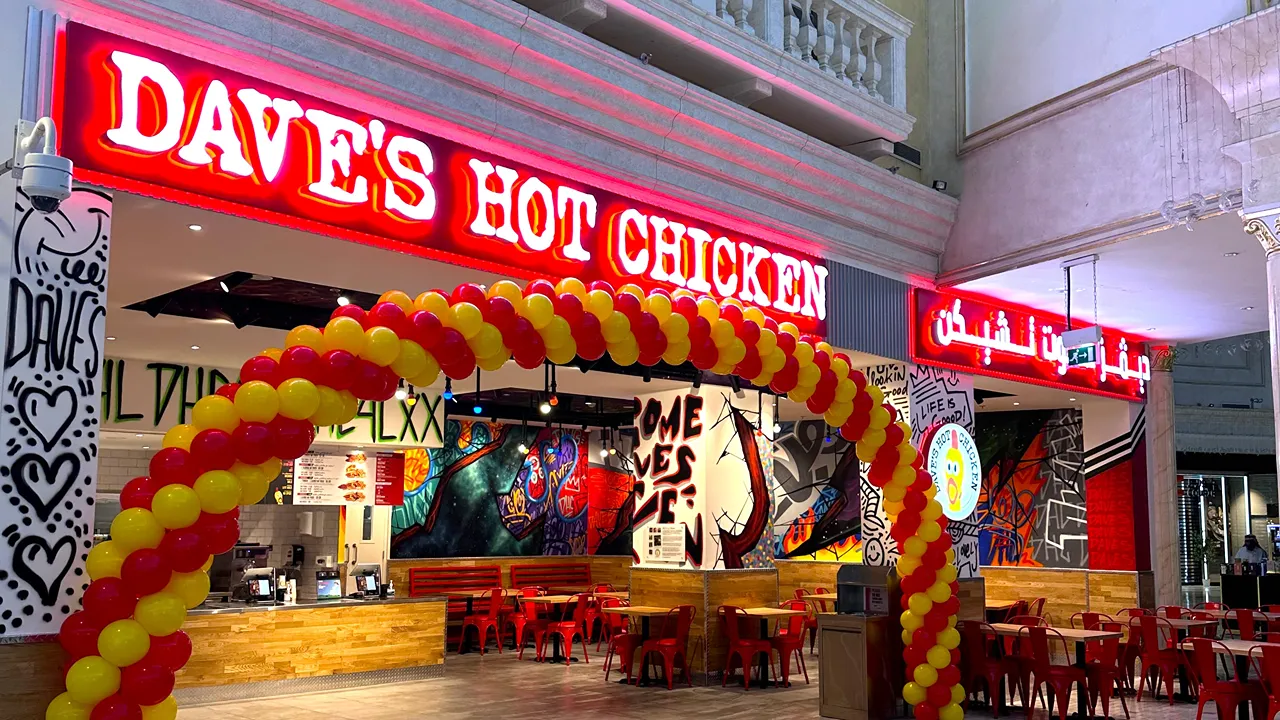  Illuminated Dave's Hot Chicken entrance with red and yellow balloon arch at Villagio Mall, Doha, Qatar, on Al Waab St.