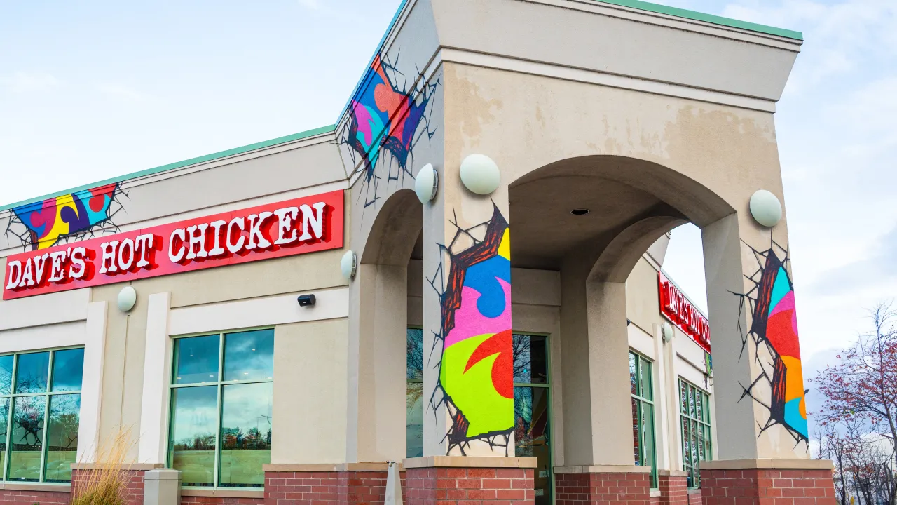 Exterior view of Dave's Hot Chicken at 3022 E 53rd St, Davenport, IA, showcasing vibrant murals and bold red signage.