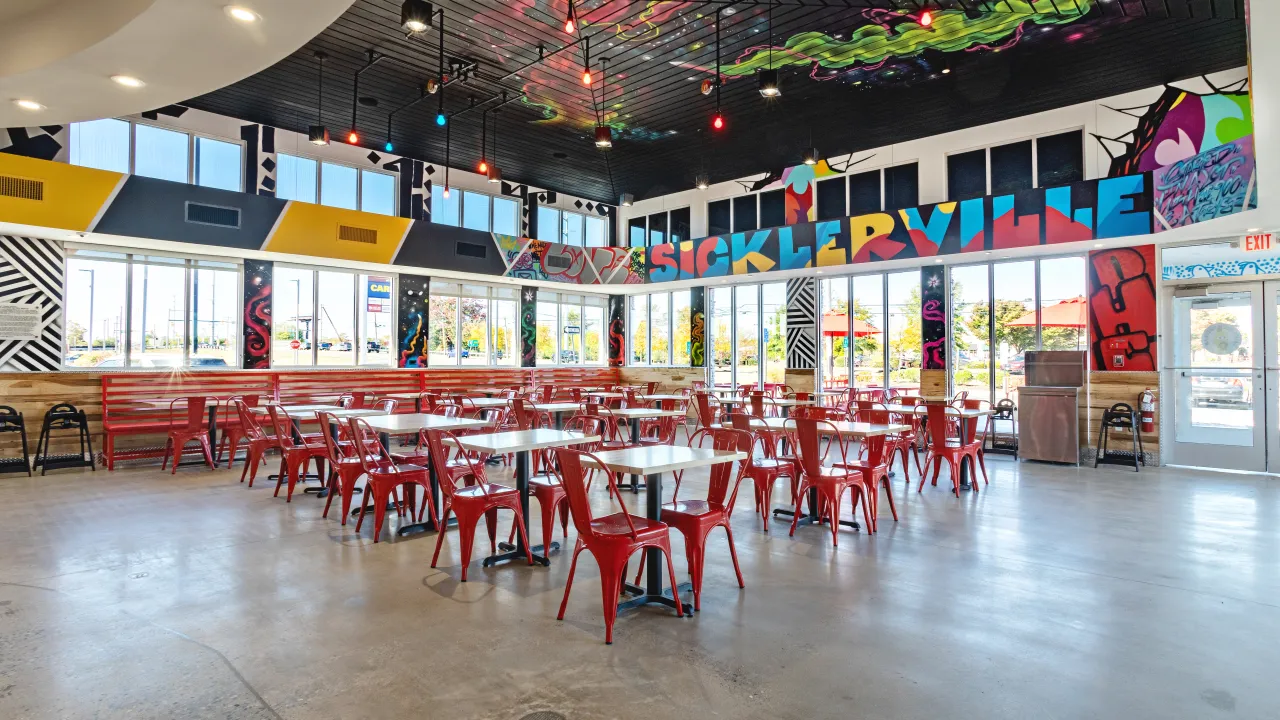 Interior view of Dave's Hot Chicken on Berlin – Cross Keys Rd, Sicklerville, NJ, featuring colorful murals and red seating.