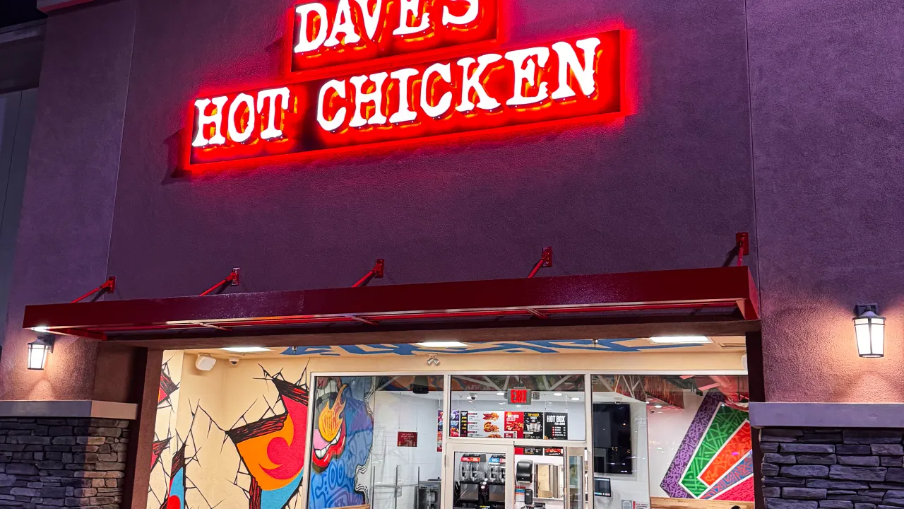 Exterior view of Dave's Hot Chicken on Colima Rd, Rowland Heights, CA, featuring vibrant murals and illuminated signage.