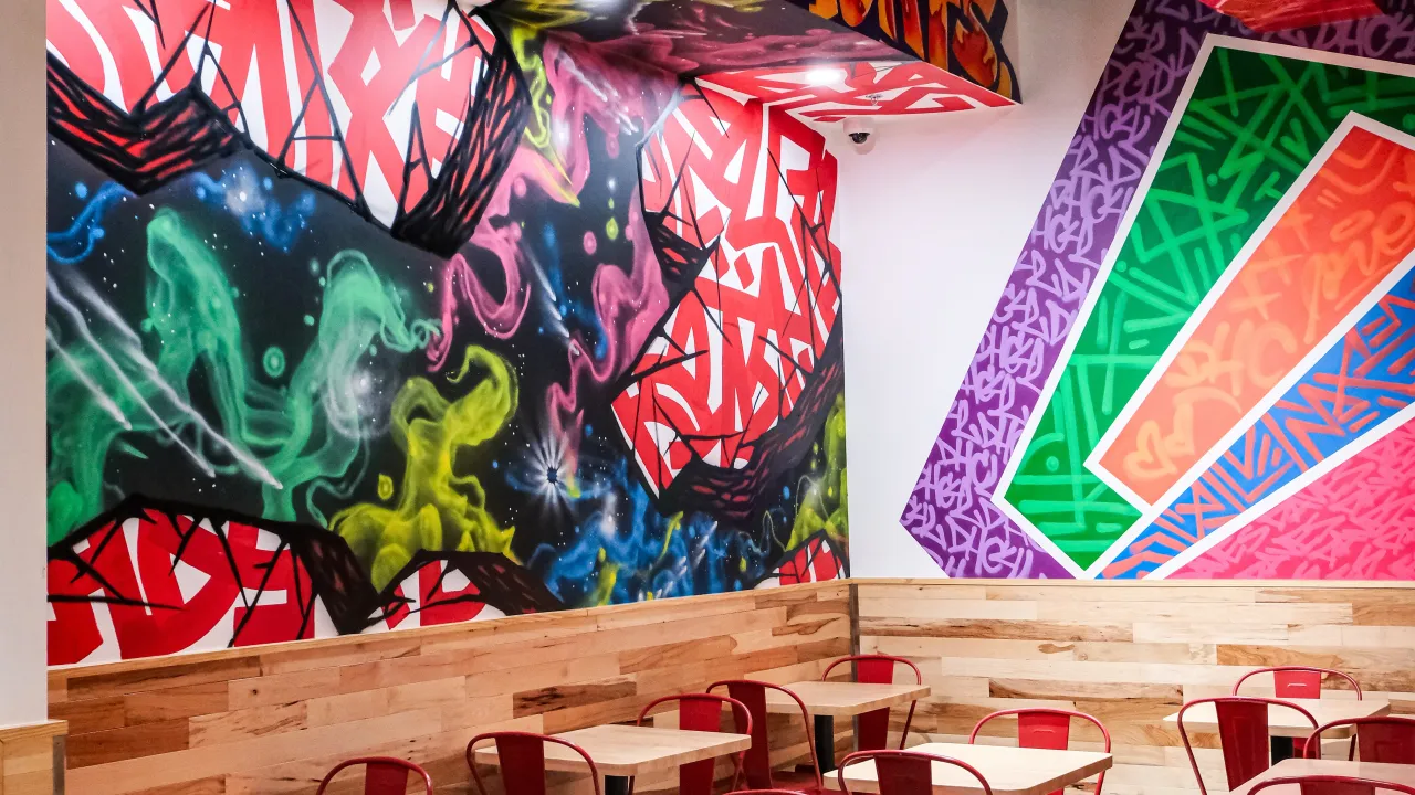 Interior view of Dave’s Hot Chicken on Colima Rd, Rowland Heights, CA, showcasing vibrant murals and casual seating.