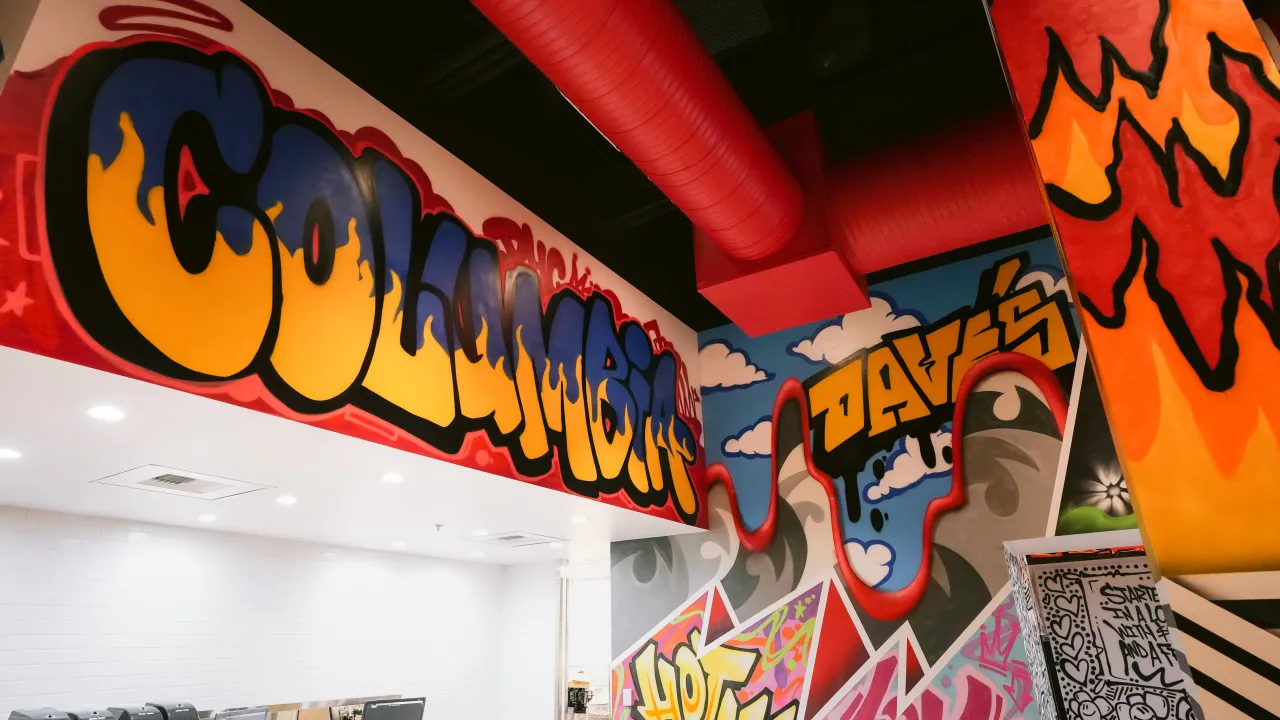 Interior view of Dave's Hot Chicken in Columbia, MD, showcasing a vibrant 'Columbia' mural and a modern, lively ambiance.