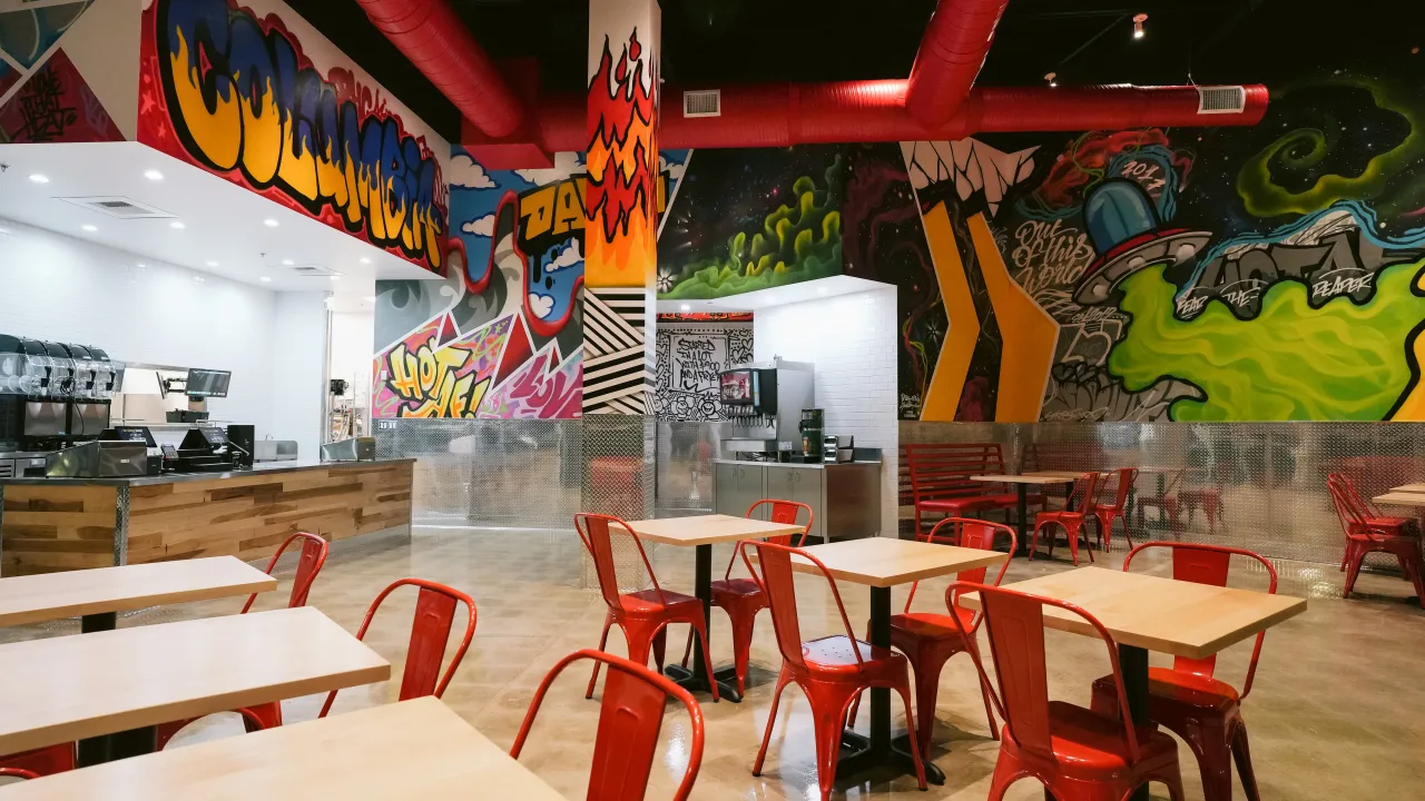 Interior view of Dave's Hot Chicken service counter in Columbia Crossing showcasing colorful murals and seating