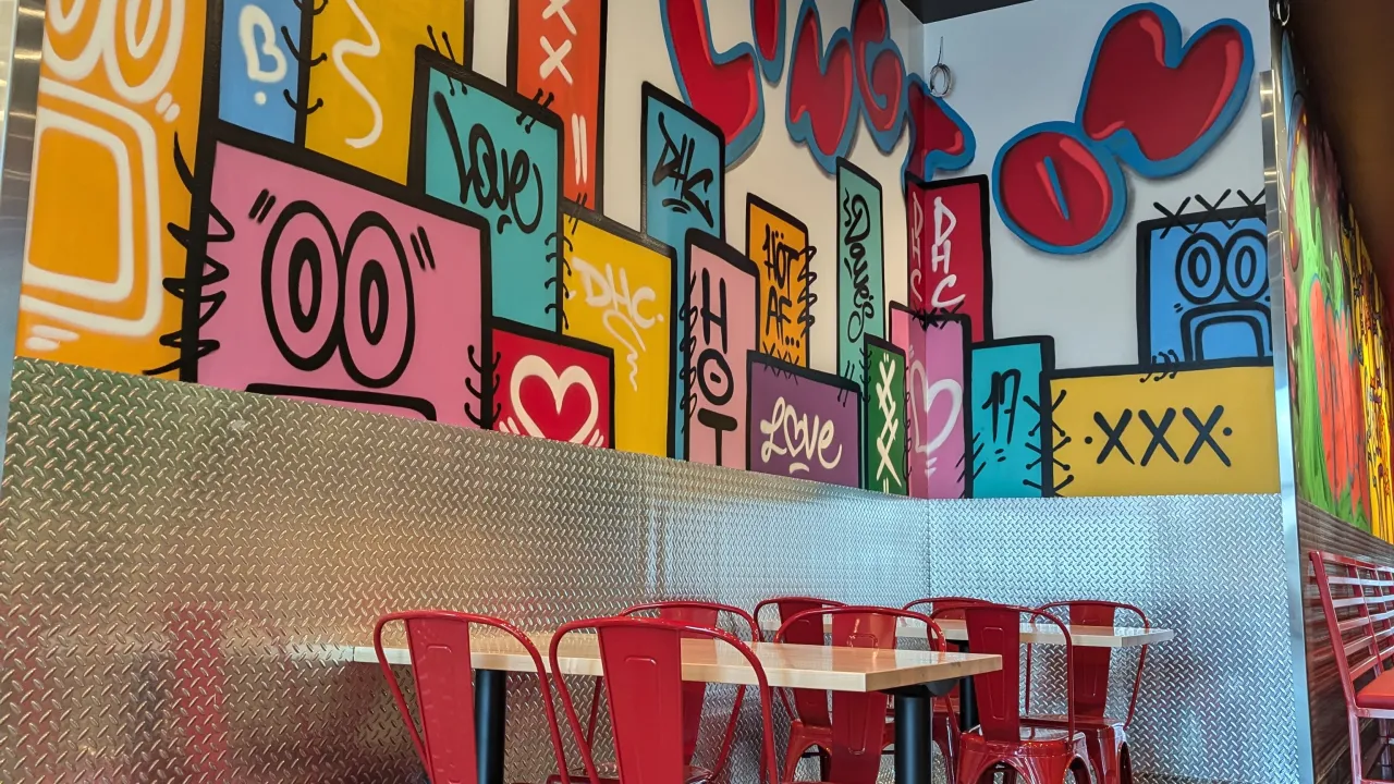 Interior view of Dave's Hot Chicken at 225 Dorset St, South Burlington, VT, showcasing colorful murals and modern seating.