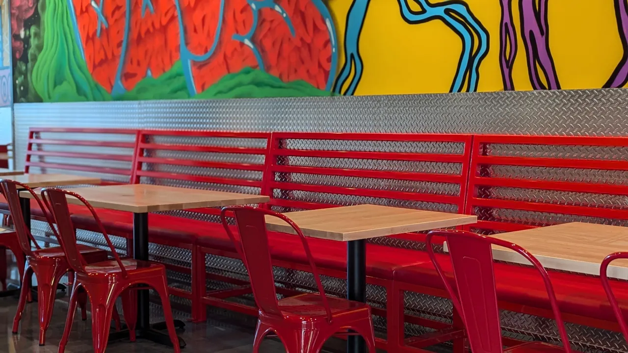 Interior view of Dave's Hot Chicken on Dorset St, South Burlington, VT, showcasing vibrant murals and red seating.