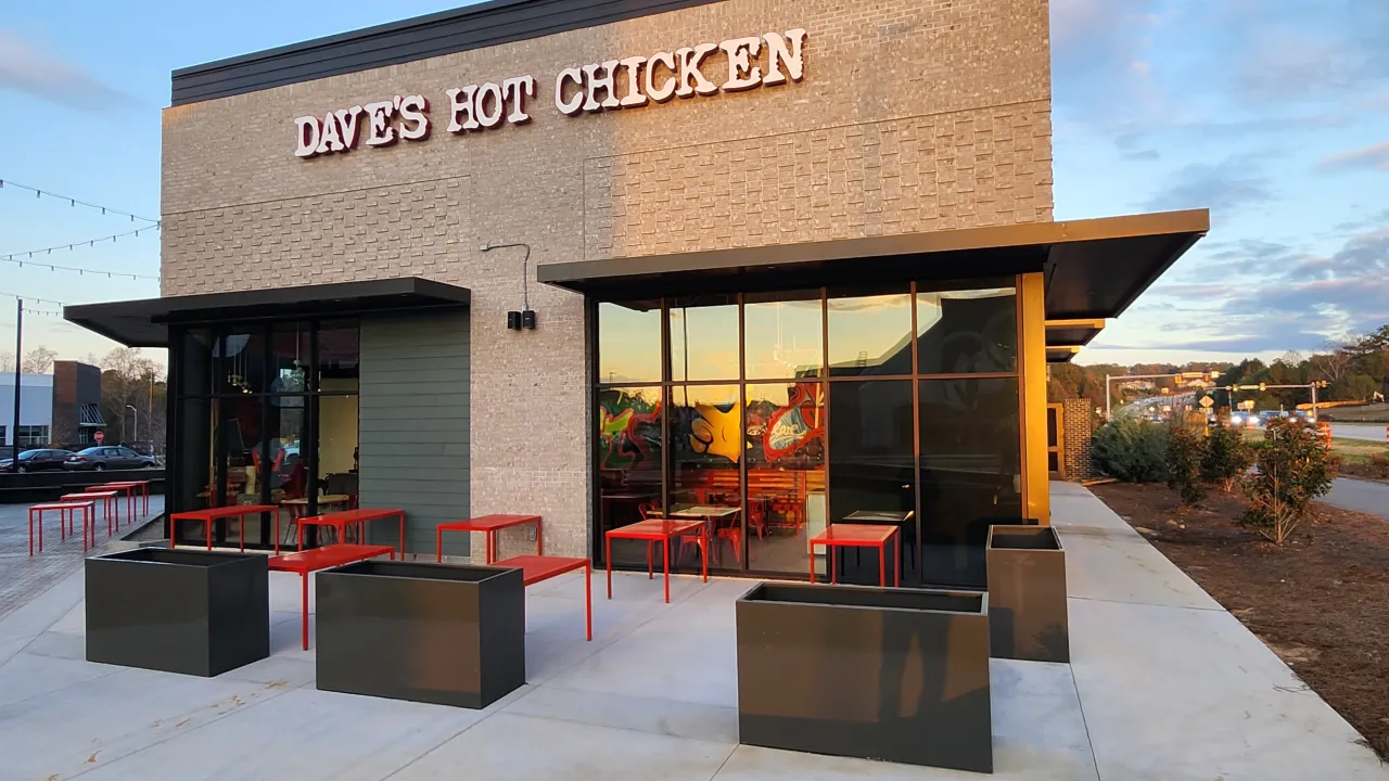 Exterior view of Dave's Hot Chicken on Dr. Calvin Jones Hwy, Wake Forest, NC, showcasing modern design and outdoor seating.