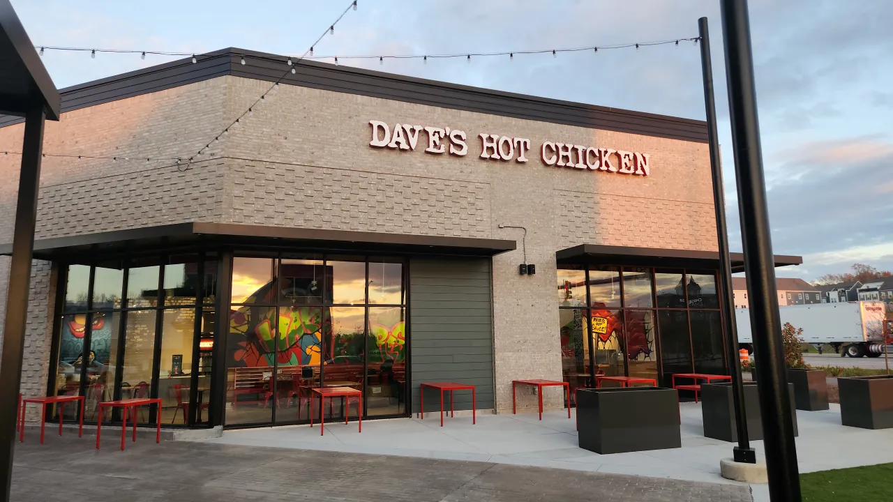 Exterior view of Dave's Hot Chicken on Dr. Calvin Jones Hwy, Wake Forest, NC, showcasing vibrant murals and outdoor seating.