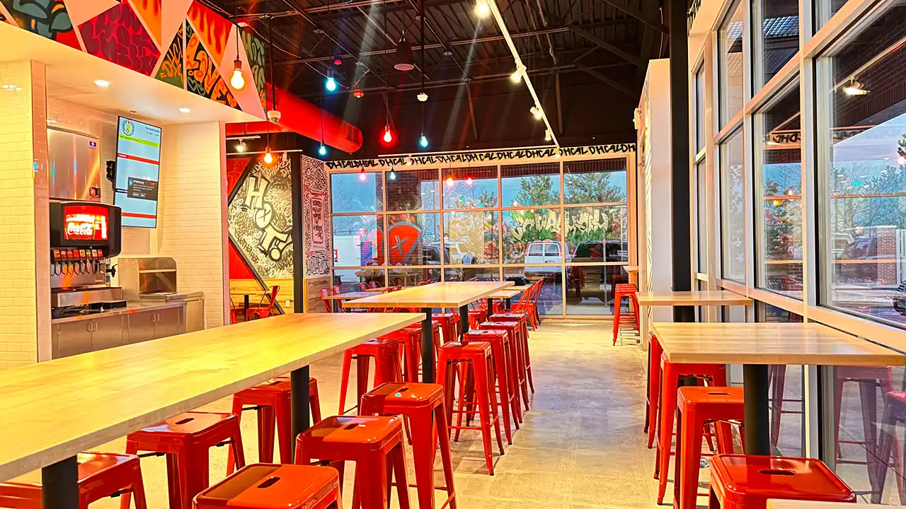 Vibrant bar seating area with red stools and modern decor inside Dave's Hot Chicken on Mayberry Dr, Highlands Ranch, CO.