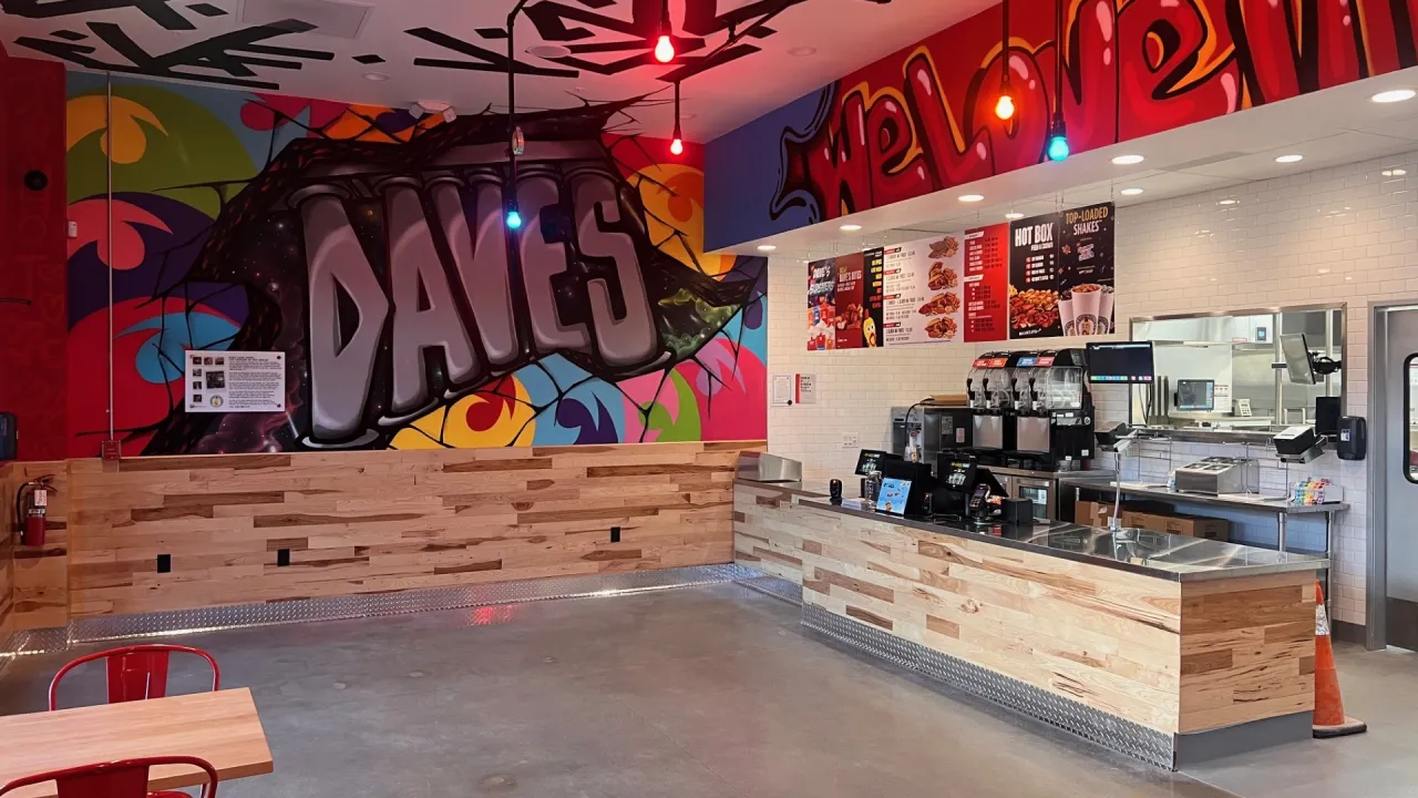 Interior view of Dave's Hot Chicken in, Brentwood, CA, showcasing vibrant murals and modern furniture.