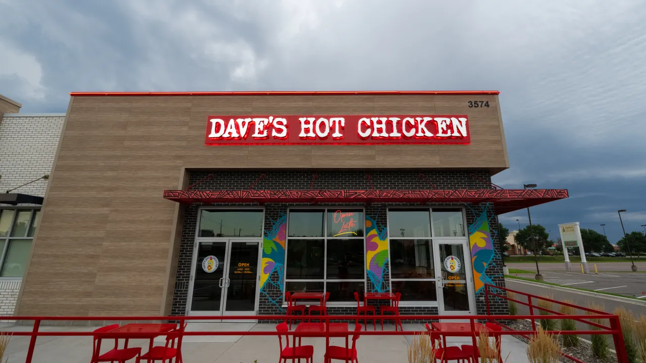 Exterior view of Dave's Hot Chicken at 3574 Main Street, Coon Rapids, MN, showcasing bright signage and outdoor seating.