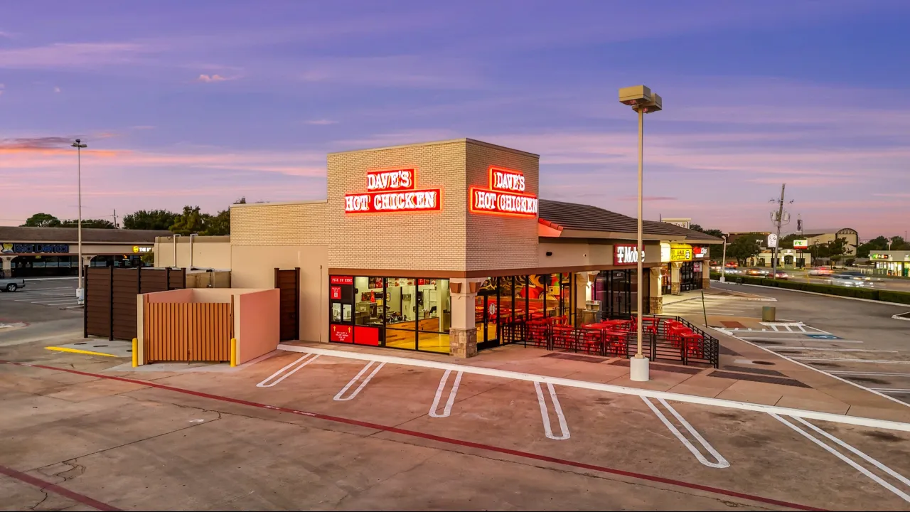 Exterior view of Dave's Hot Chicken on W Main St, Lewisville, TX, showcasing bright red signage and outdoor seating.