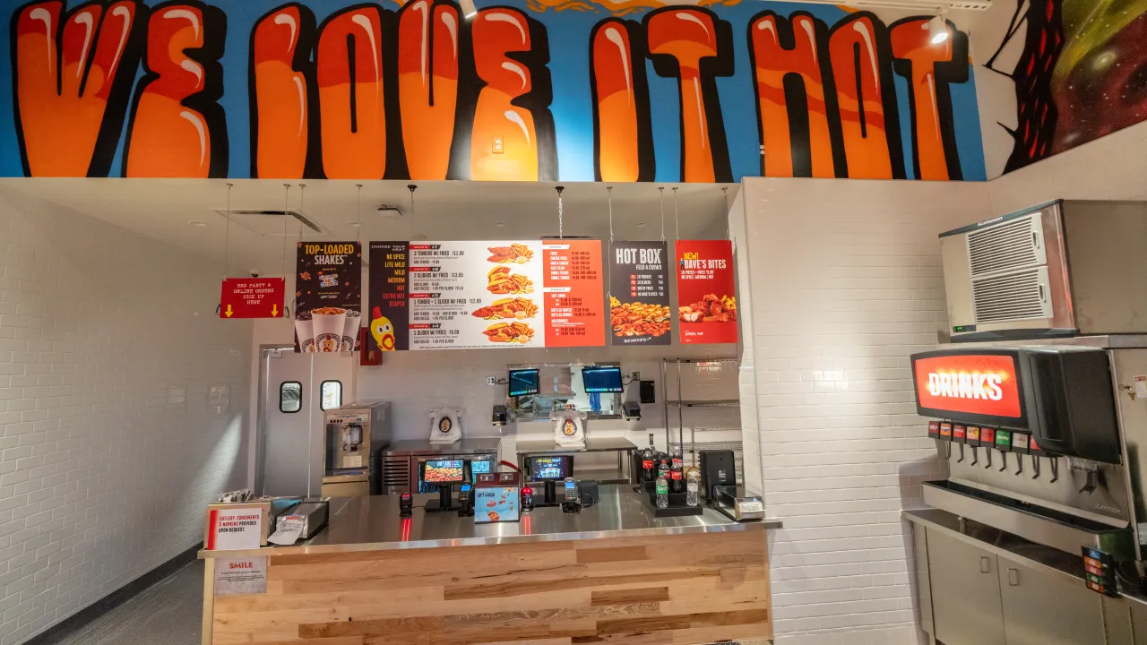 Interior view of Dave’s Hot Chicken at 3574 Main Street, Coon Rapids, MN, featuring a colorful mural and menu boards.