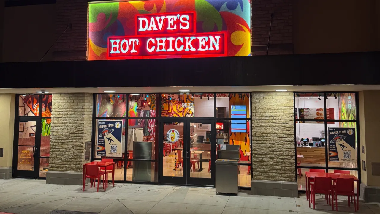 Exterior view of Dave's Hot Chicken at 9670 Main Street, Fairfax, VA, showcasing vibrant murals and red outdoor seating.