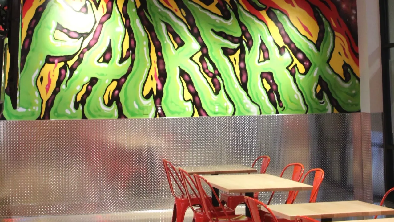 Interior view of Dave's Hot Chicken at 9670 Main Street, Fairfax, VA, showcasing vibrant green mural and red seating.