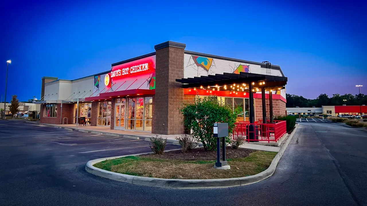 Exterior view of Dave's Hot Chicken on Monroe St, Toledo, OH, showcasing vibrant red signage and outdoor seating.