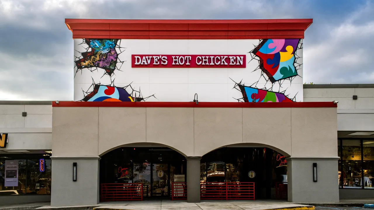 Exterior view of Dave's Hot Chicken on Montgomery Hwy, Vestavia Hills, AL, showcasing vibrant murals and bold signage.