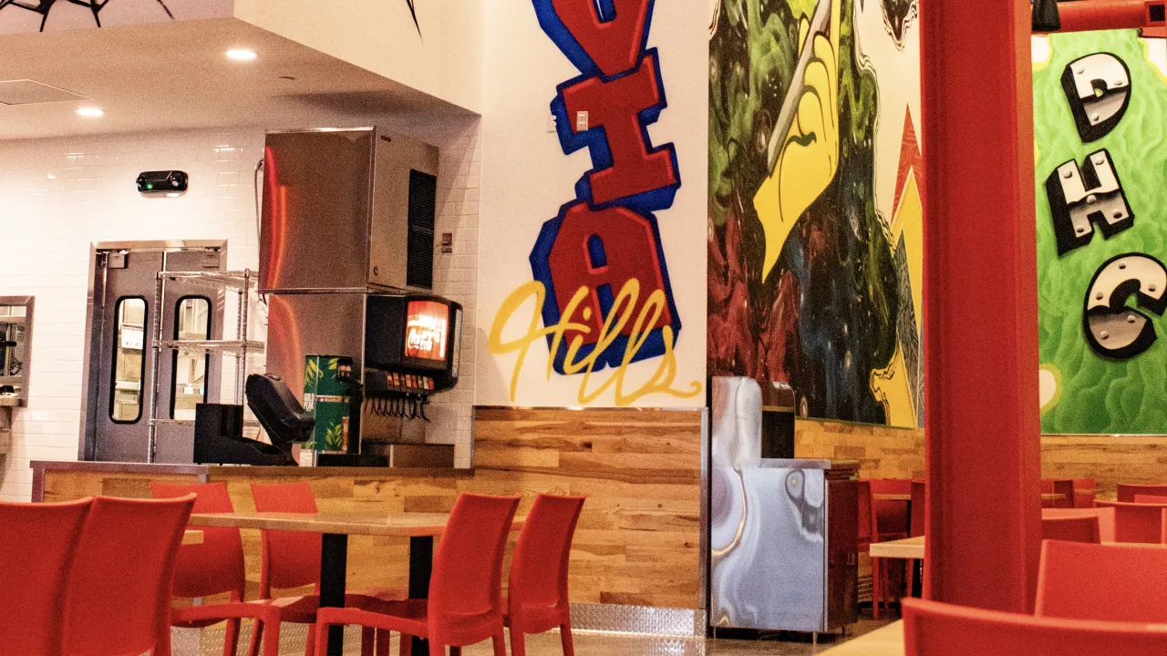 Interior view of Dave's Hot Chicken in Vestavia Hills, AL, showcasing vibrant murals and modern red seating.