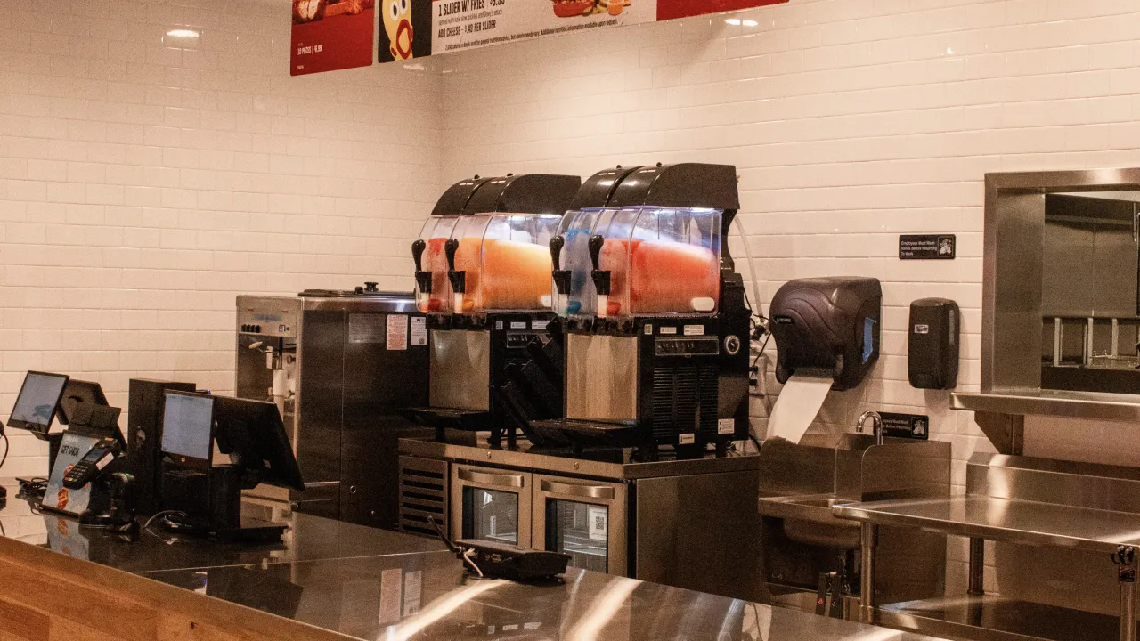 Interior view of the counter at Dave’s Hot Chicken, 632 Montgomery Hwy, Vestavia Hills, AL, featuring cash registers and frozen drink machines.