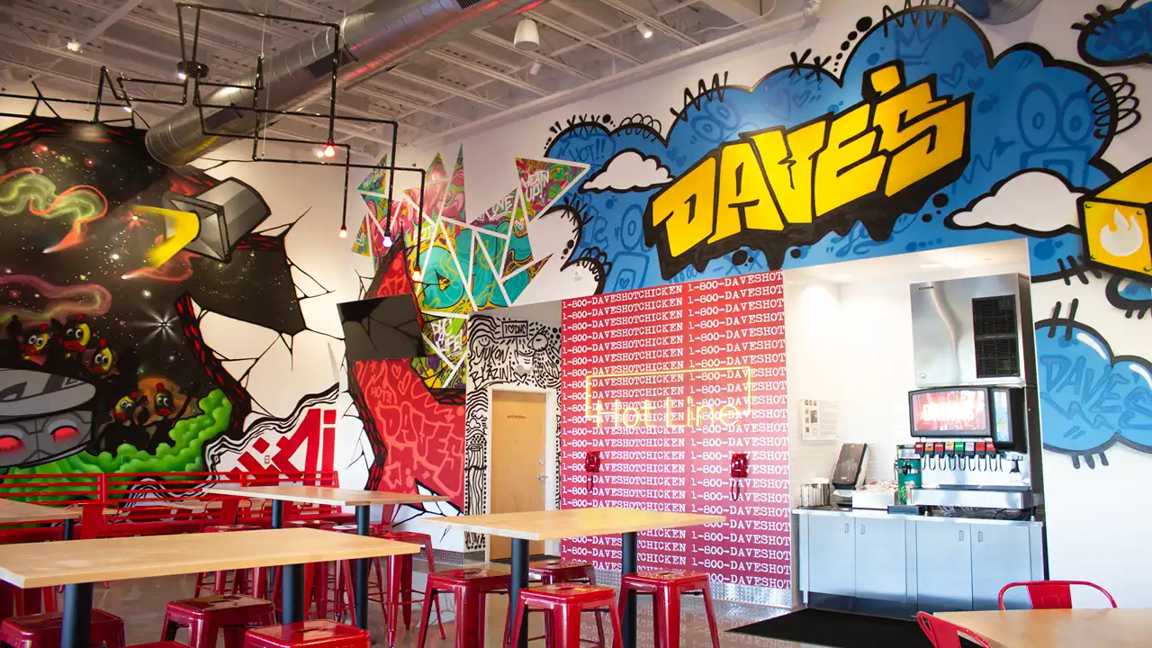 Colorful interior mural with bold graffiti, bright red seating, and soda fountain inside Dave’s Hot Chicken on NW 10th St, Yukon, OK.