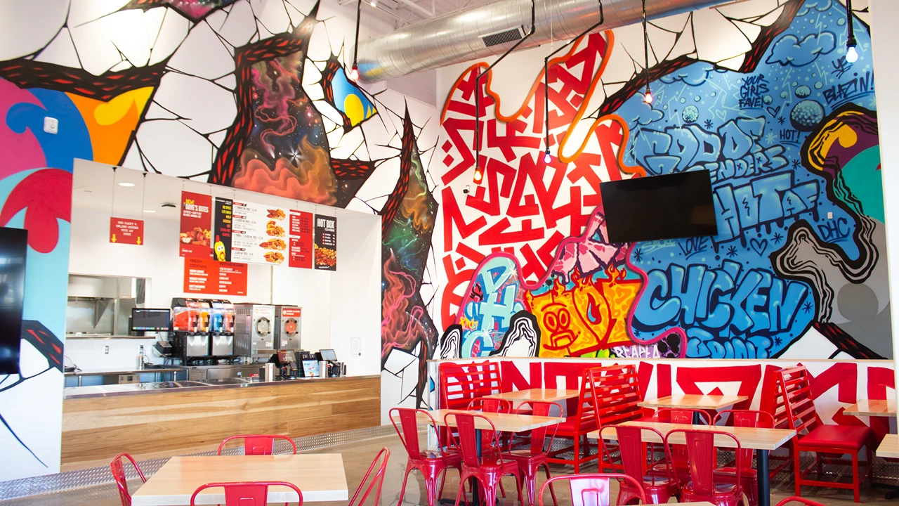 Vibrant wall art with red and blue graffiti behind the order counter at Dave’s Hot Chicken, NW 10th St location near I-40 in Yukon, OK.