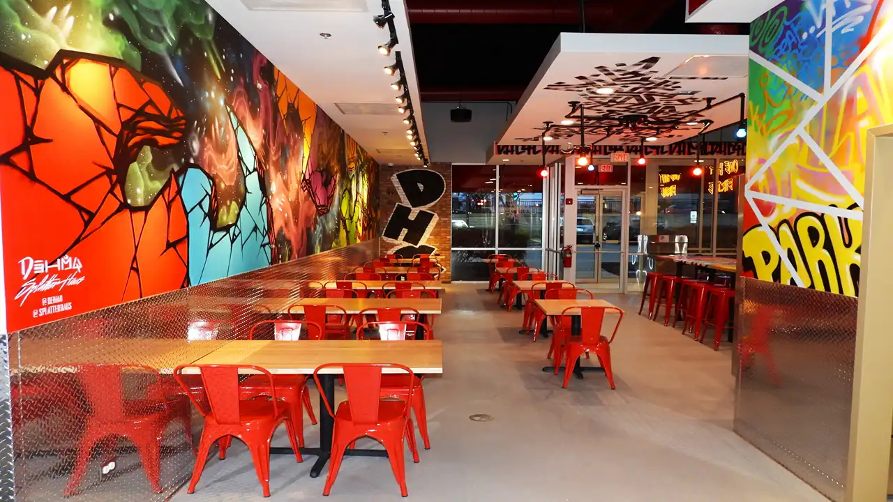 Modern dining area at Dave’s Hot Chicken on LaGrange Rd, Orland Park, with vibrant murals and stylish red furniture.