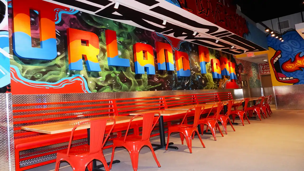 Bright mural reading 'Orland Park' in bold colors inside Dave’s Hot Chicken on LaGrange Rd, showcasing spacious seating arrangements.