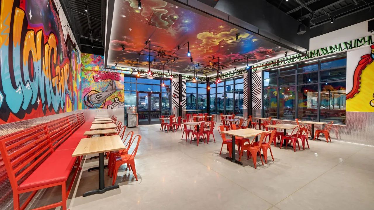 Interior view of Dave's Hot Chicken in Willow Grove, PA, showcasing the seating area and vibrant wall and roof murals.