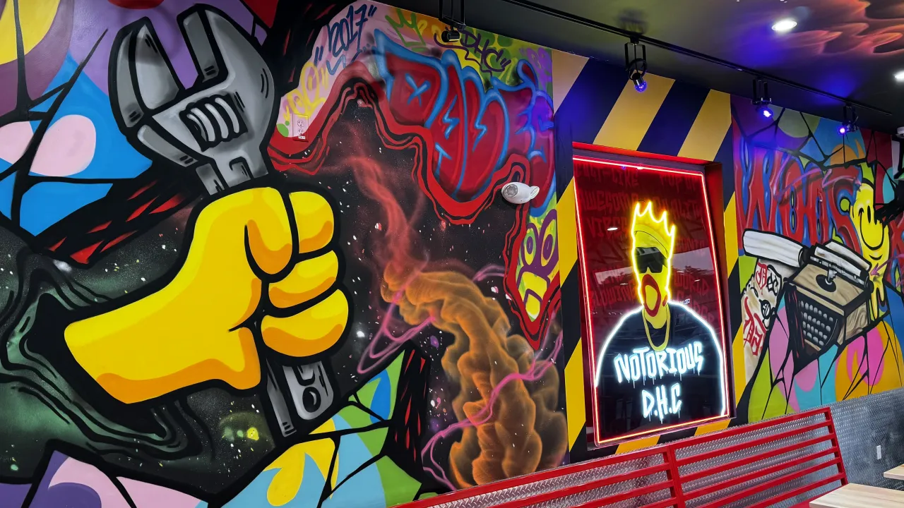 Interior view of Dave's Hot Chicken at 41 Park Ave, Worcester, MA, showcasing vibrant murals and modern seating.