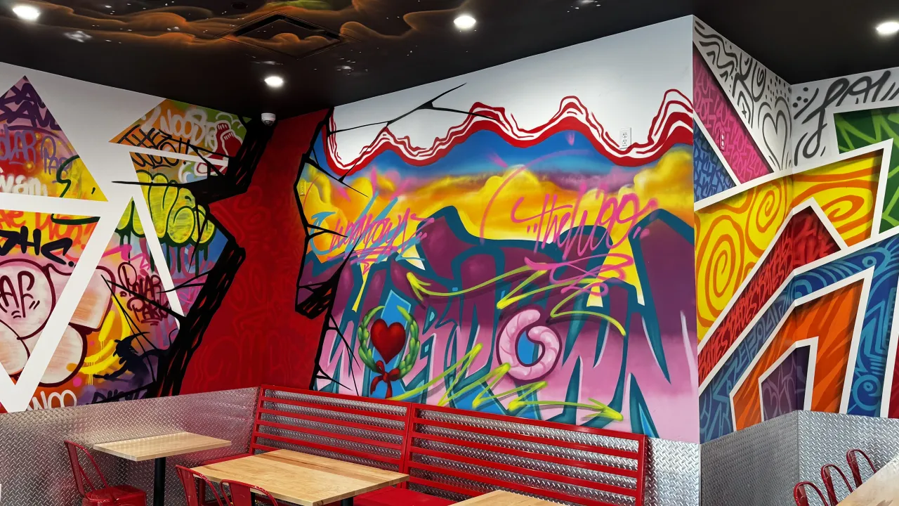 Interior view of Dave's Hot Chicken on Park Ave, Worcester, MA, showcasing vibrant murals and red seating.