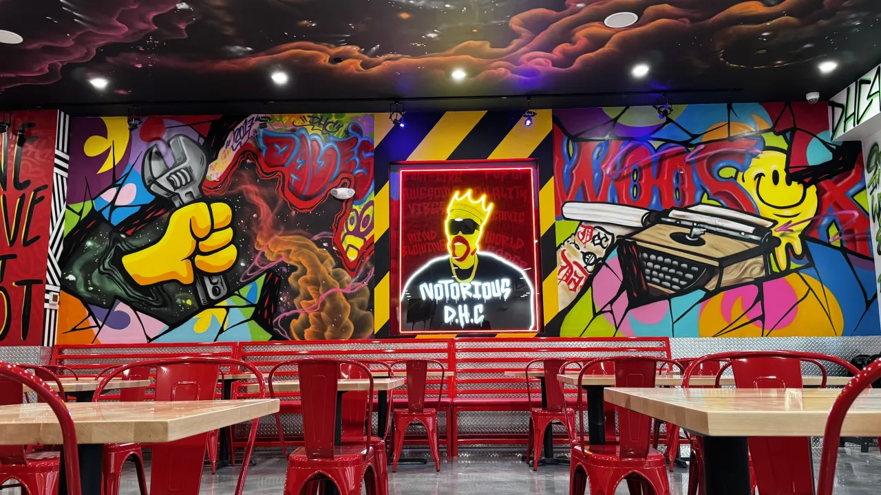 Interior view of Dave's Hot Chicken on Park Ave, Worcester, MA, showcasing vibrant murals and red seating.