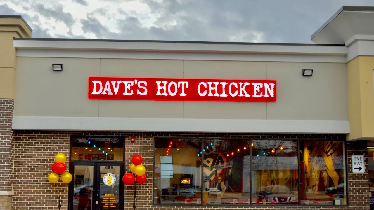 Exterior view of Dave's Hot Chicken in White Plains, NY, showcasing bright red signage and colorful balloons.