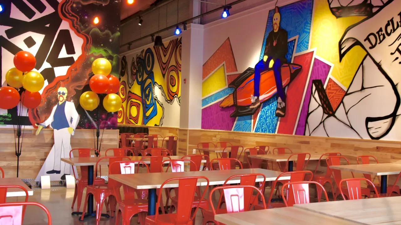 Interior view of Dave's Hot Chicken on Tarrytown Rd, White Plains, NY, showcasing colorful murals and red seating.