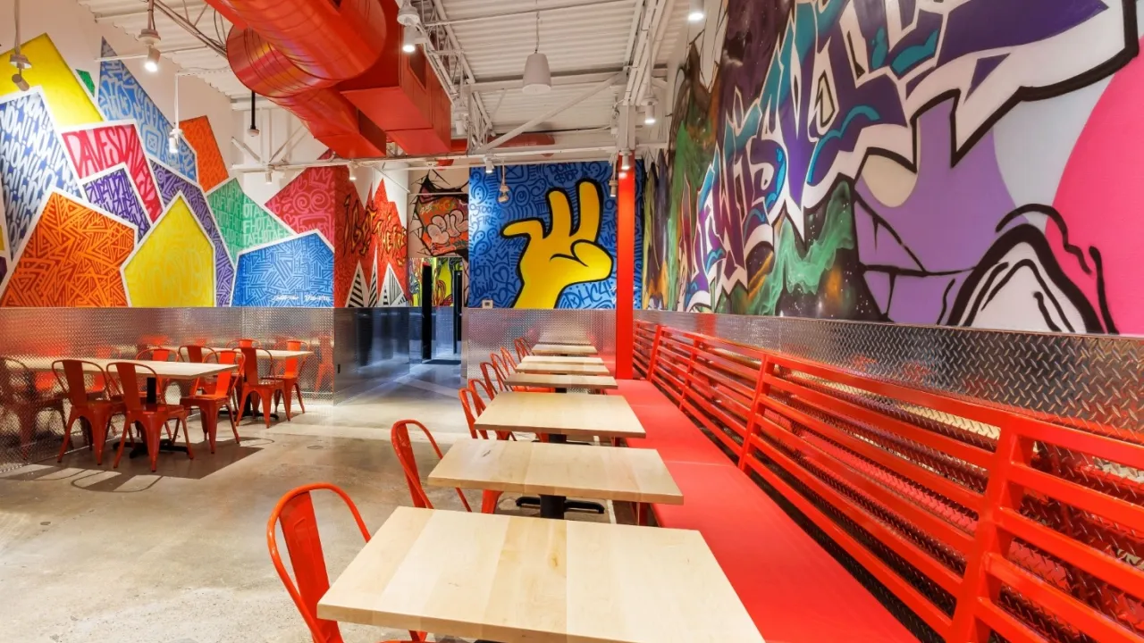 Interior view of Dave's Hot Chicken in Lewisville, TX, showcasing vibrant murals and modern seating.