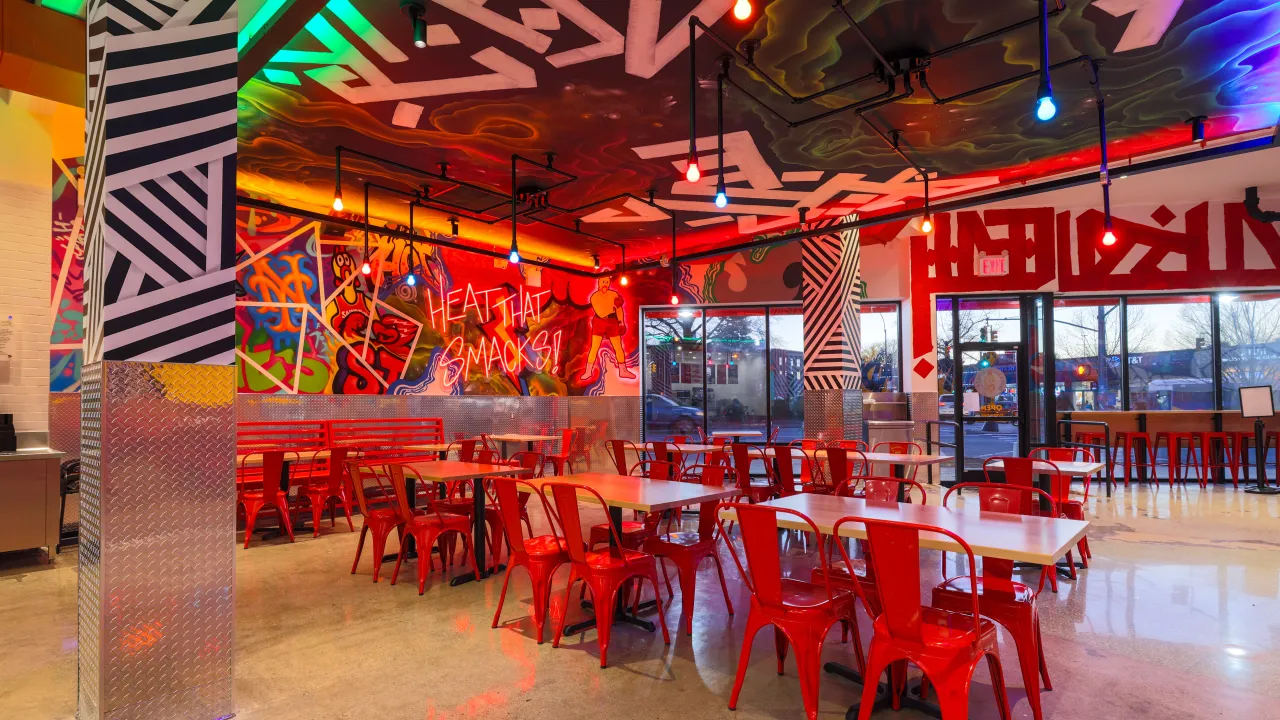Interior view of Dave's Hot Chicken on 61-45 188th St, Fresh Meadows, NY, featuring vibrant murals and red chairs.