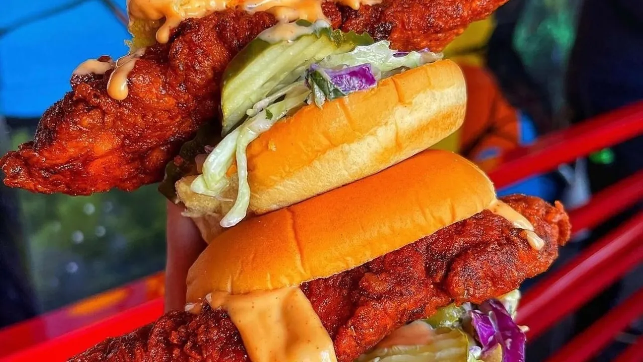 Stacked spicy chicken sandwiches with pickles and slaw, showcasing the delicious offerings at Dave's Hot Chicken in Odessa, FL.