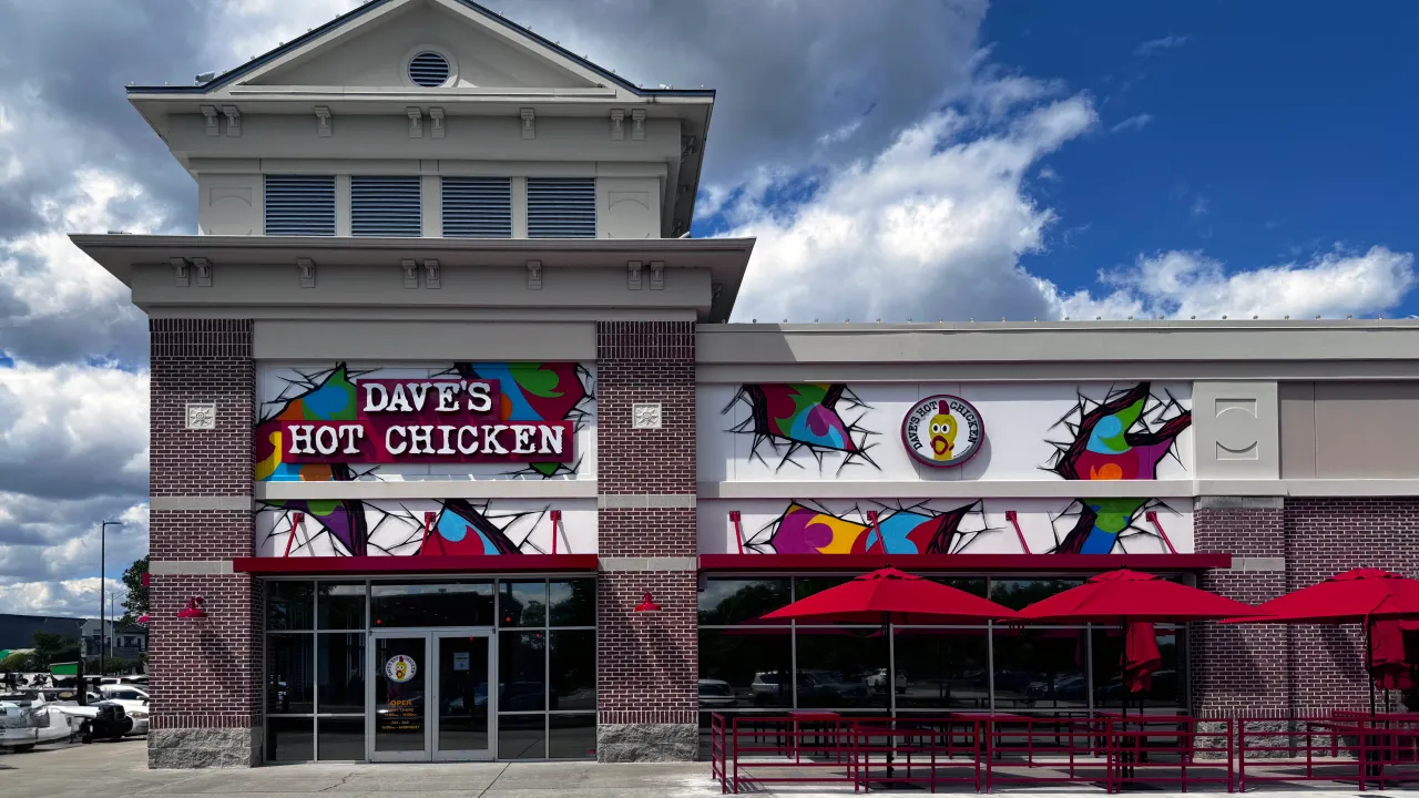Exterior view of Dave's Hot Chicken at 10261 River Marsh Dr, Jacksonville, FL, showcasing vibrant murals and red umbrellas.