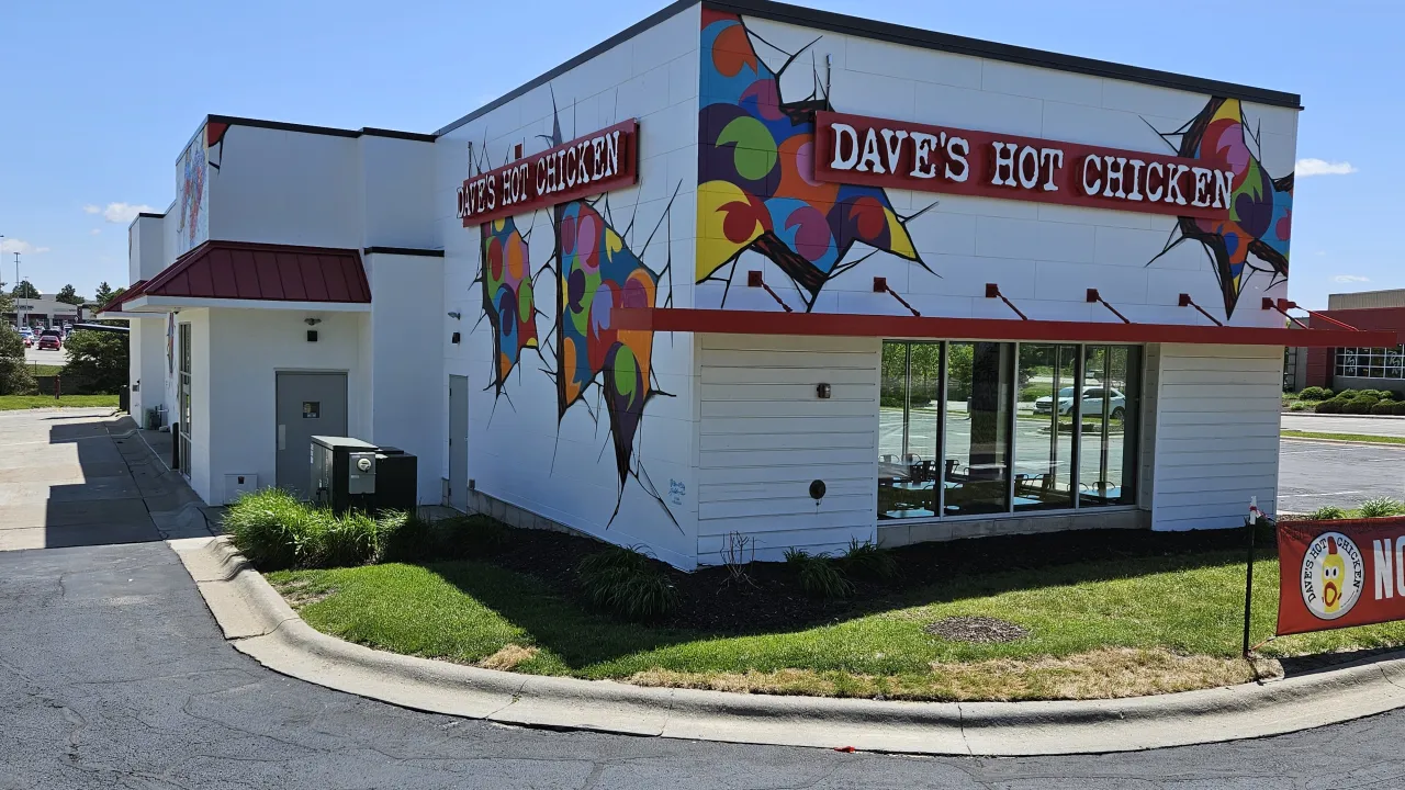 Exterior view of Dave's Hot Chicken on 2615 S. 180th St, Omaha, NE, featuring vibrant murals and large windows.