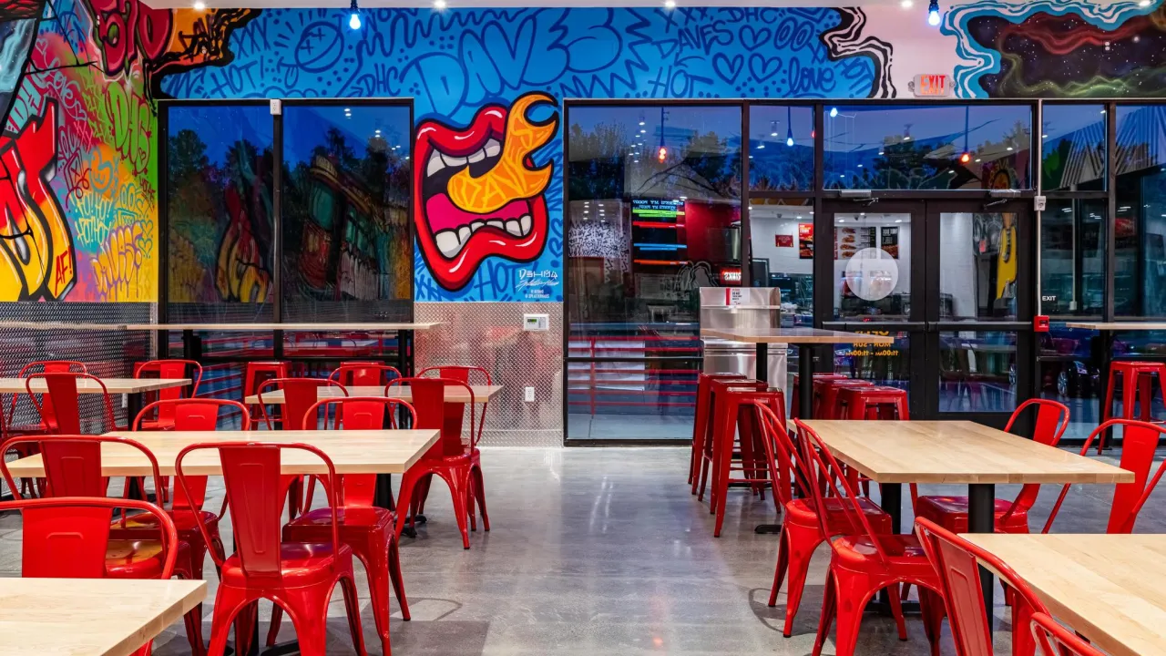 Interior view of Dave's Hot Chicken at 700 Commerce Blvd, Dickson City, PA, showcasing vibrant murals and red seating.