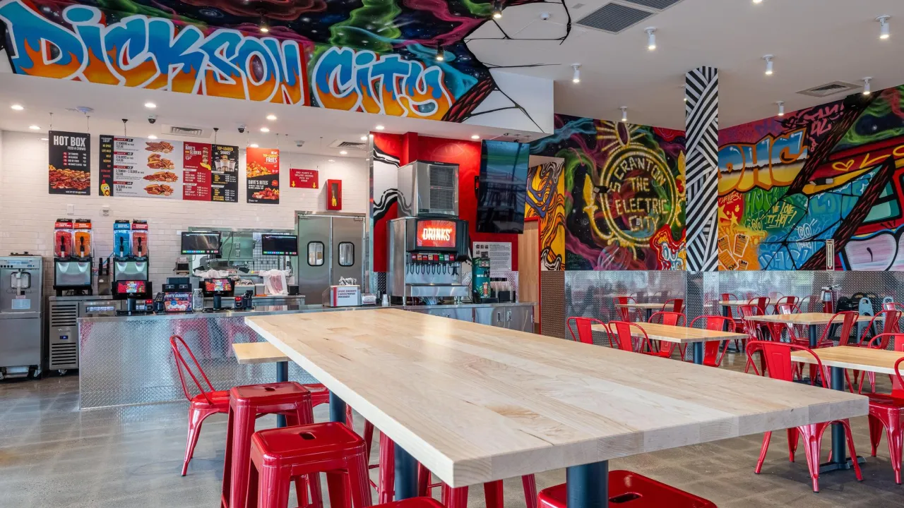 Interior view of Dave's Hot Chicken on Commerce Blvd, Dickson City, PA, showcasing vibrant murals and modern seating.
