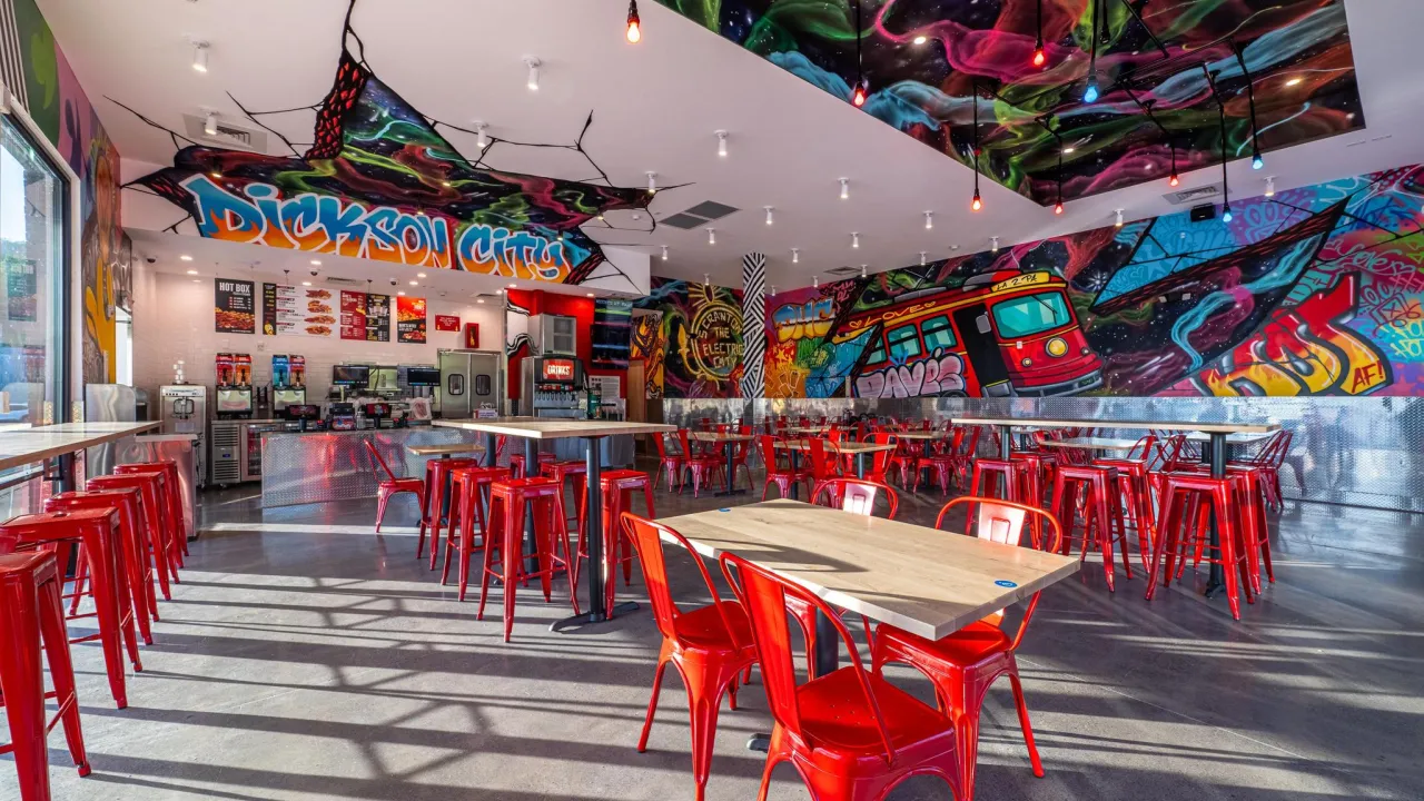 Interior view of Dave’s Hot Chicken at 700 Commerce Blvd, Dickson City, PA, showcasing vibrant murals and red seating.