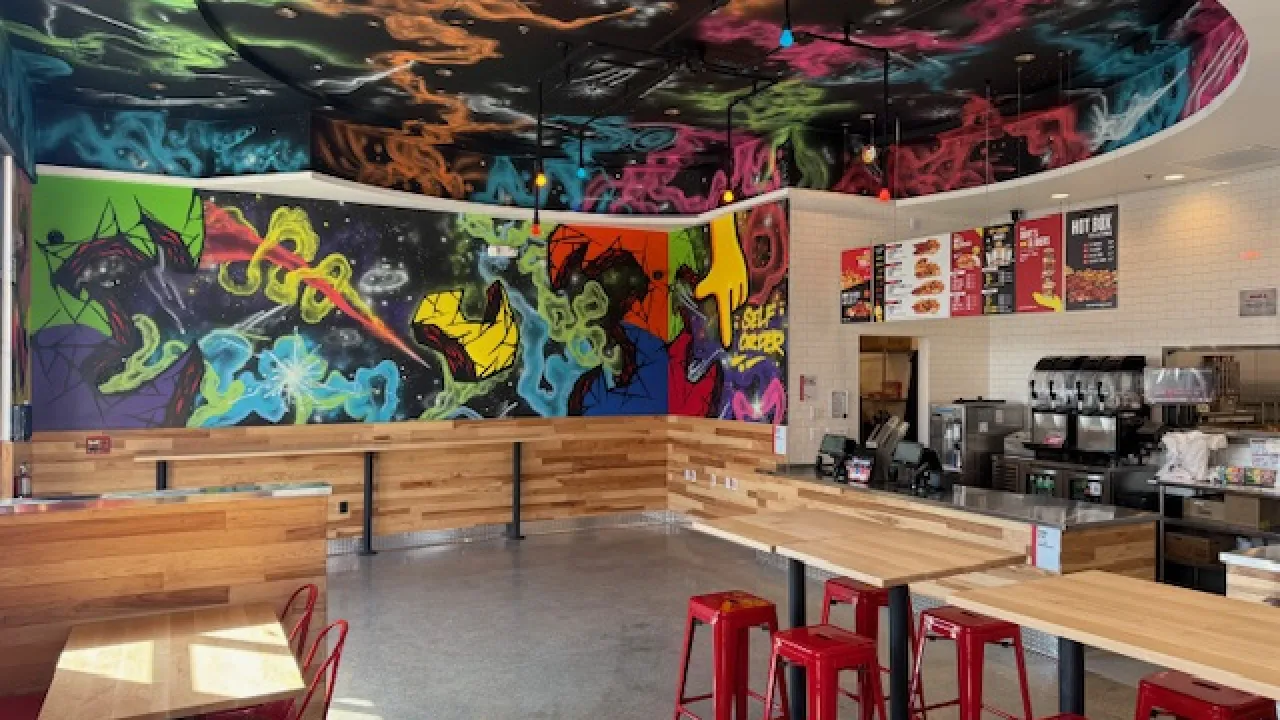 Interior view of Dave's Hot Chicken at 4213 First St, Livermore, CA, showcasing vibrant murals and modern seating.
