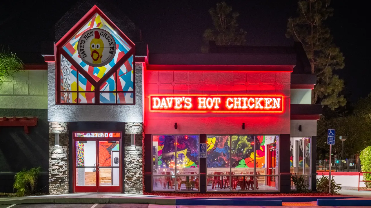 Exterior view of Dave's Hot Chicken on Kingston Rd, Pickering, ON, showcasing vibrant murals and bright red signage.