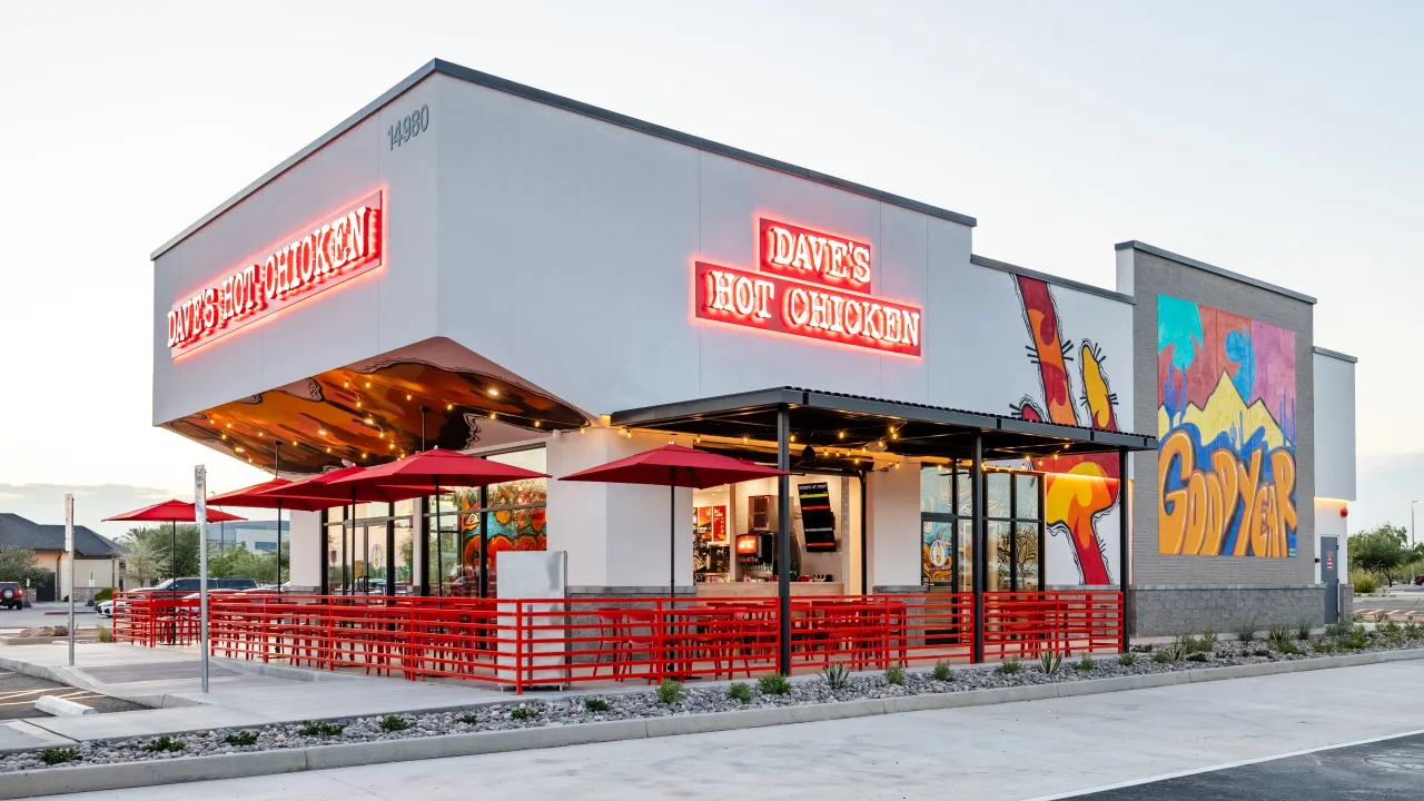 Exterior view of Dave's Hot Chicken at 14980 W. McDowell Rd, Goodyear, AZ, showcasing vibrant murals and red patio seating.