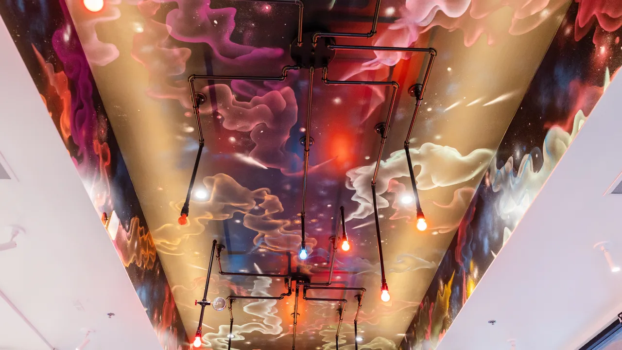 Interior view of the colorful ceiling at Dave's Hot Chicken on W. McDowell Rd, Goodyear, AZ, featuring artistic lighting and murals.