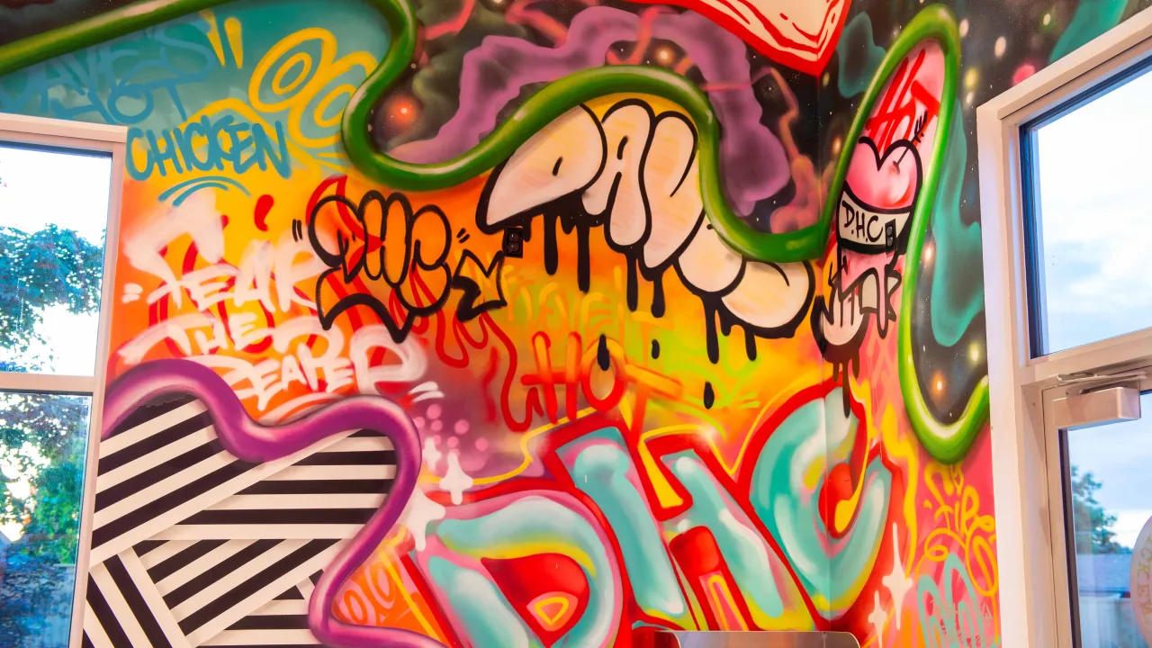Interior view of Dave's Hot Chicken on Mohawk Blvd, Springfield, OR, showcasing vibrant graffiti art on the walls.