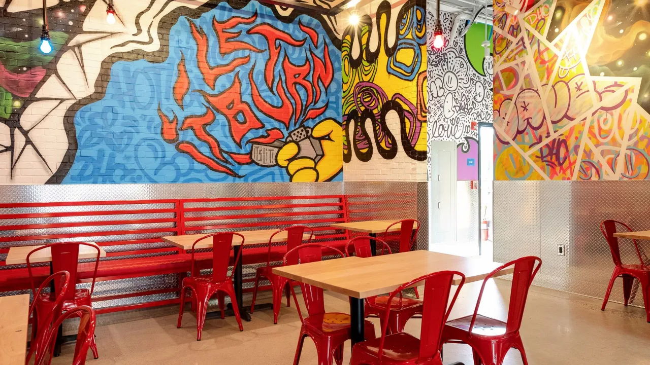 Interior view of Dave's Hot Chicken at 218 N West End Blvd, Quakertown, PA, showcasing vibrant murals and red seating.
